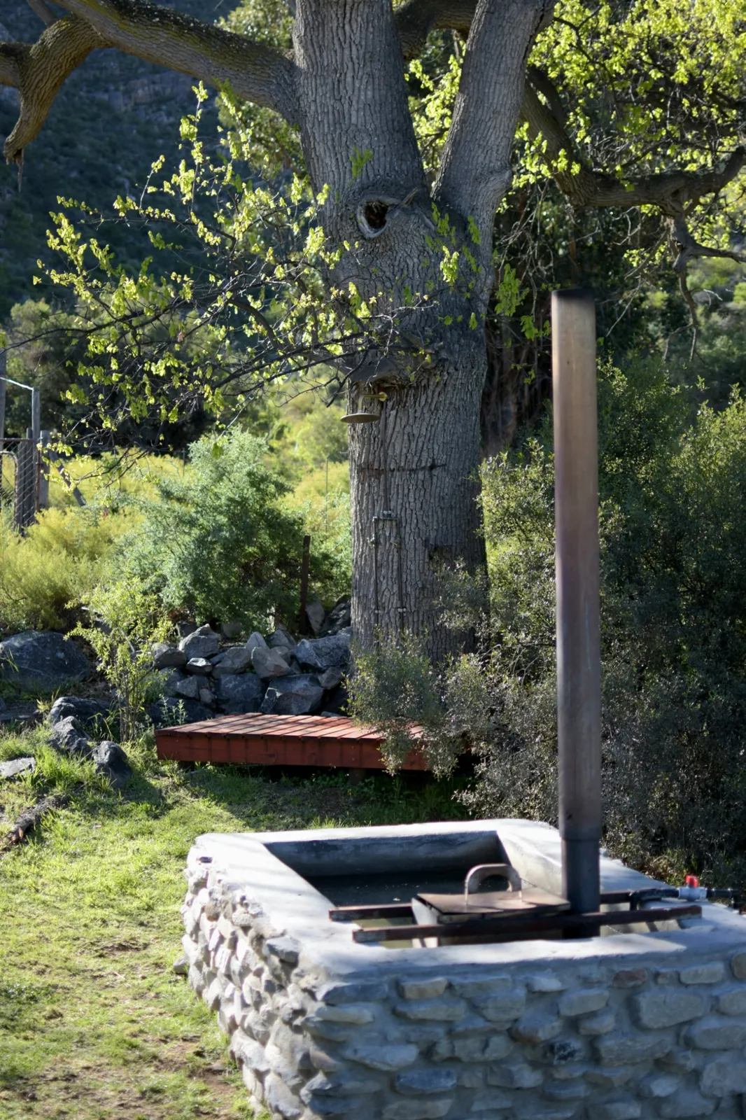 Oakron's private stone hot tub and outdoor shower beside an old oak tree
